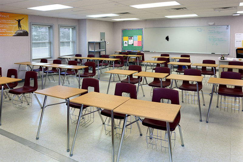 Empty modular classroom with rows of single desks, maroon chairs & a whiteboard in Pedricktown, NJ