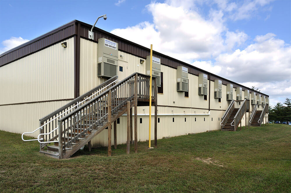 Beige flexspace modular building by Mobilease Modular Space with exterior stairs and small windows  