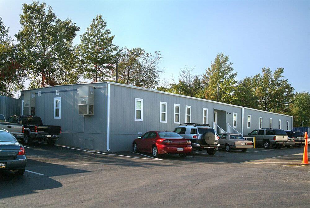 Gray Flexspace Modular Office Building by Mobilease Modular Space with parked cars and trees
