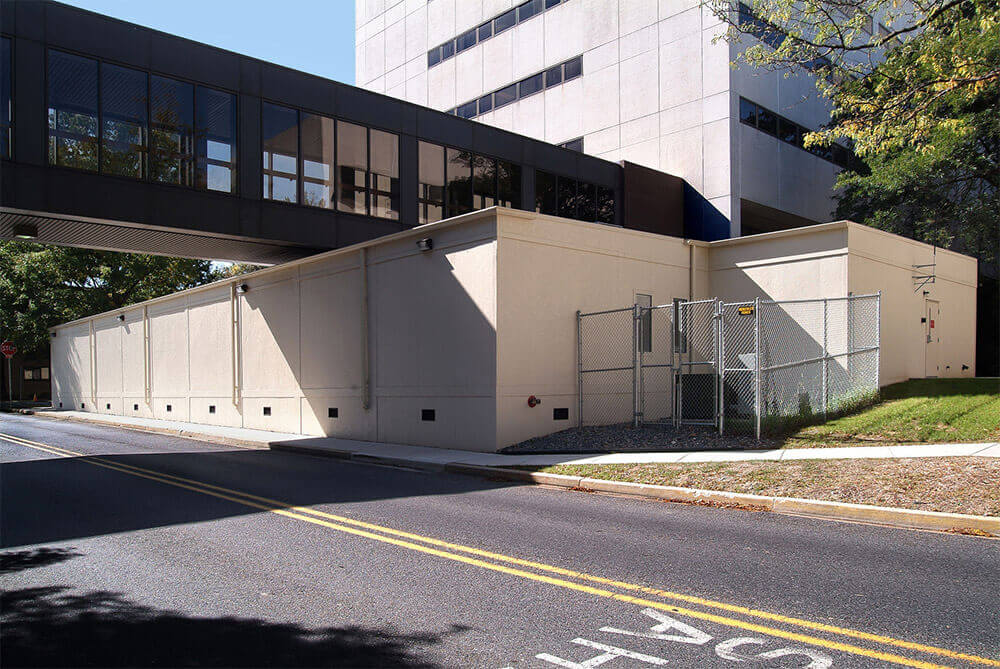 Low beige flexspace modular building by Mobilease Modular Space by roadway with chain‑link fence