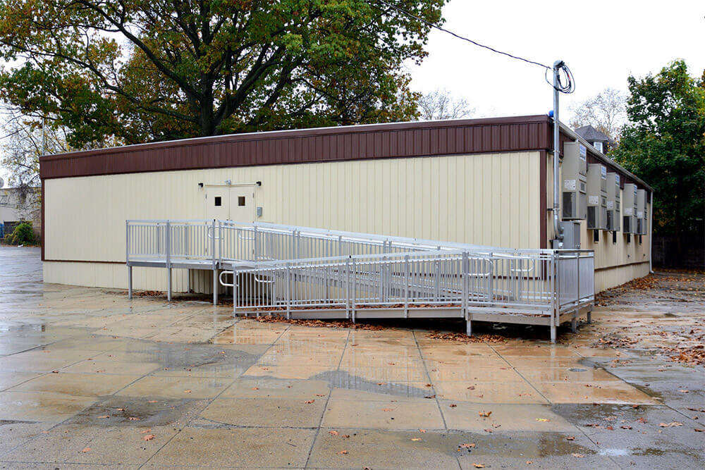 modular flexspace building with accessible ramp, wet paved ground, and autumn trees in the background