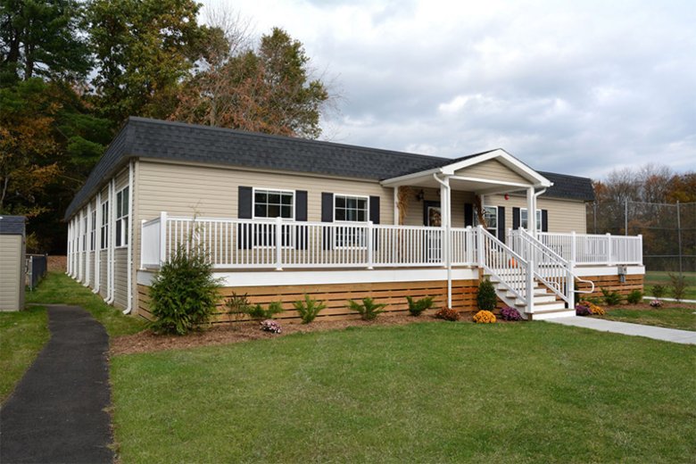 Educational modular building with ramp and welcoming entrance, surrounded by campus greenery