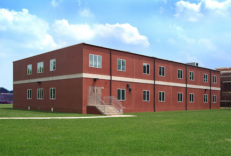 Two-story red modular building by Mobilease Modular Space on a green lawn.